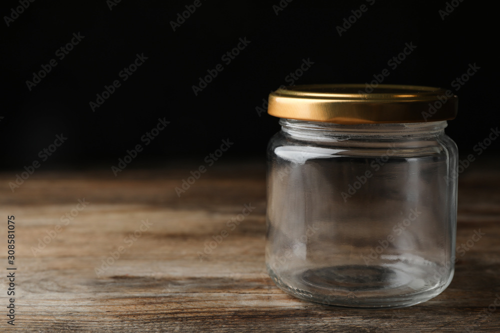 Empty glass jar on wooden table, space for text