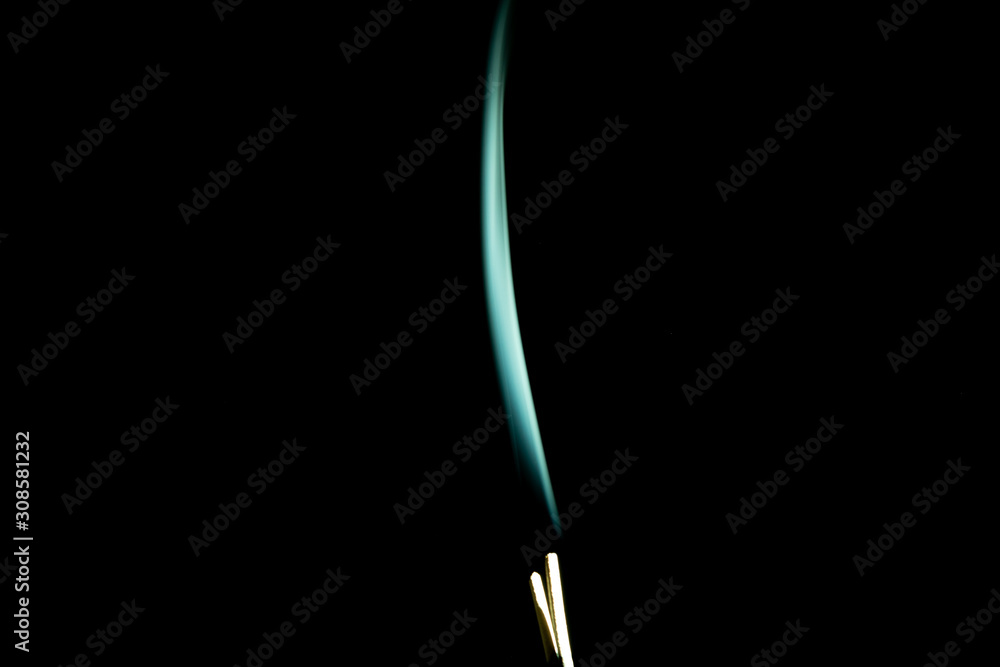 Single green trail of incense smoke drifting upwards on a black background Single green trail of incense smoke drifting upwards on a black background
