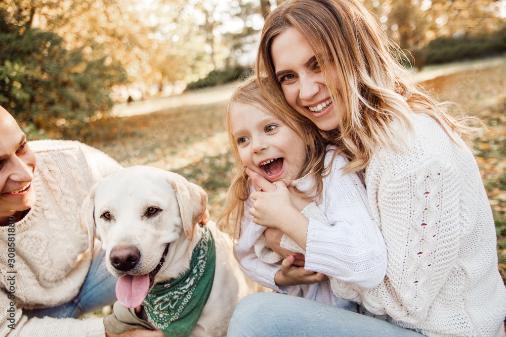 Happy beautiful family with dog labrador is having fun are sitting on green grass in park. Happy beautiful family with dog labrador is having fun are sitting on green grass in park.