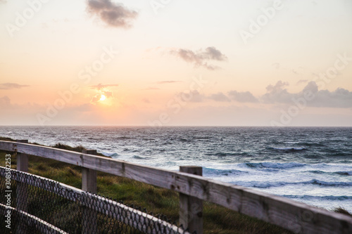 Lovely Beautiful Sunset in Cornwall England waves crashing against the base of the tall dangerous cliffs  fenced off to prevent suicide of young people or accidental death from falling.