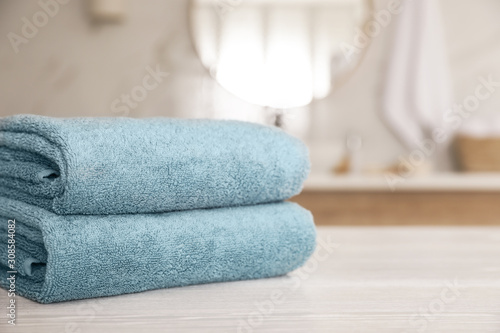 Stack of clean towels on white wooden table in bathroom. Space for text