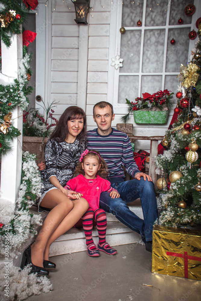 family dad mom and daughter sitting on the steps of the house with Christmas decor family dad mom and daughter sitting on the steps of the house with Christmas decor