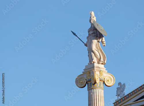 Athena and small sphinx statue under blue sky background, space for text