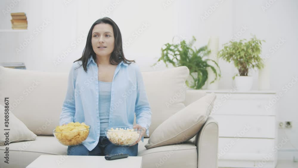 Slowmo. Happy woman is holding huge deep plates with pop corn and chips. She is coming out of the focus. 4K. Slowmo. Happy woman is holding huge deep plates with pop corn and chips. She is coming out of the focus. 4K.