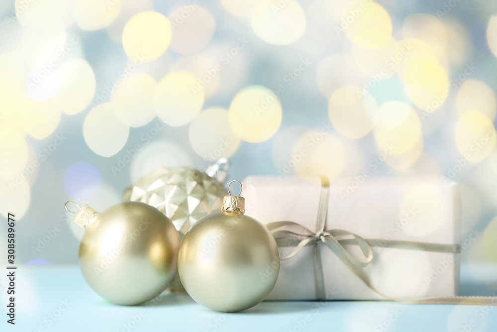 Beautiful Christmas balls with gift on table against blurred lights Beautiful Christmas balls with gift on table against blurred lights