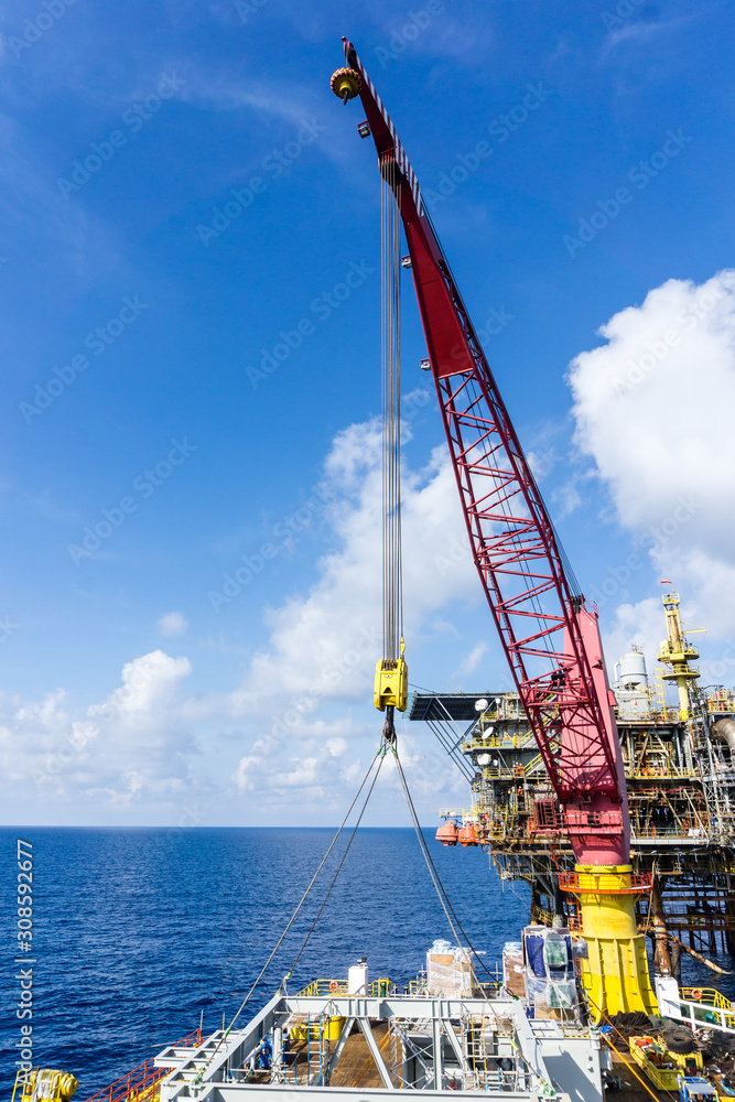 Offshore crane on board a construction work barge performing heavy lifting of a frame strcuture from a work barge at oil field