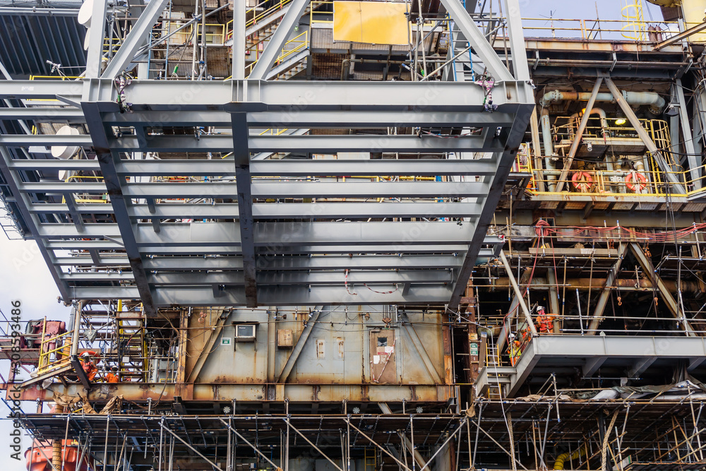 A structure frame being lifted by a construction work barge crane to an oil production platform at oil field A structure frame being lifted by a construction work barge crane to an oil production platform at oil field