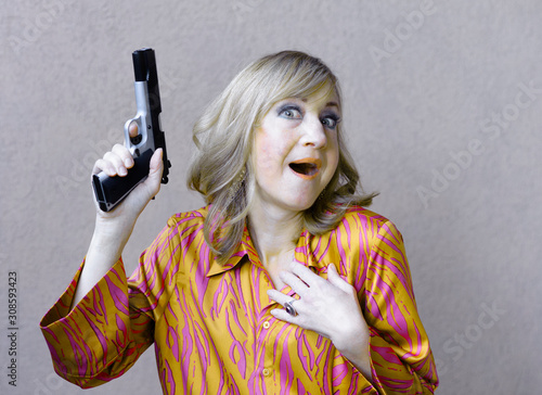 Surprised fashionable woman holds a large loaded gun for self defense.  photo