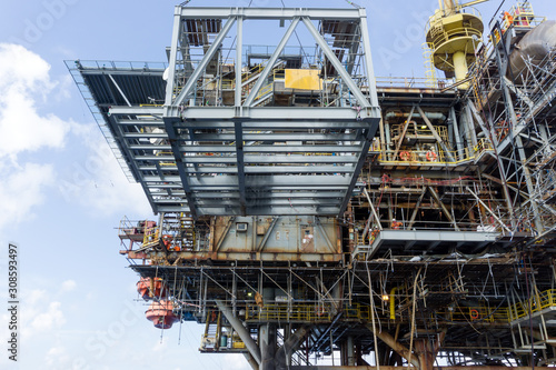 A structure frame being lifted by a construction work barge crane to an oil production platform at oil field