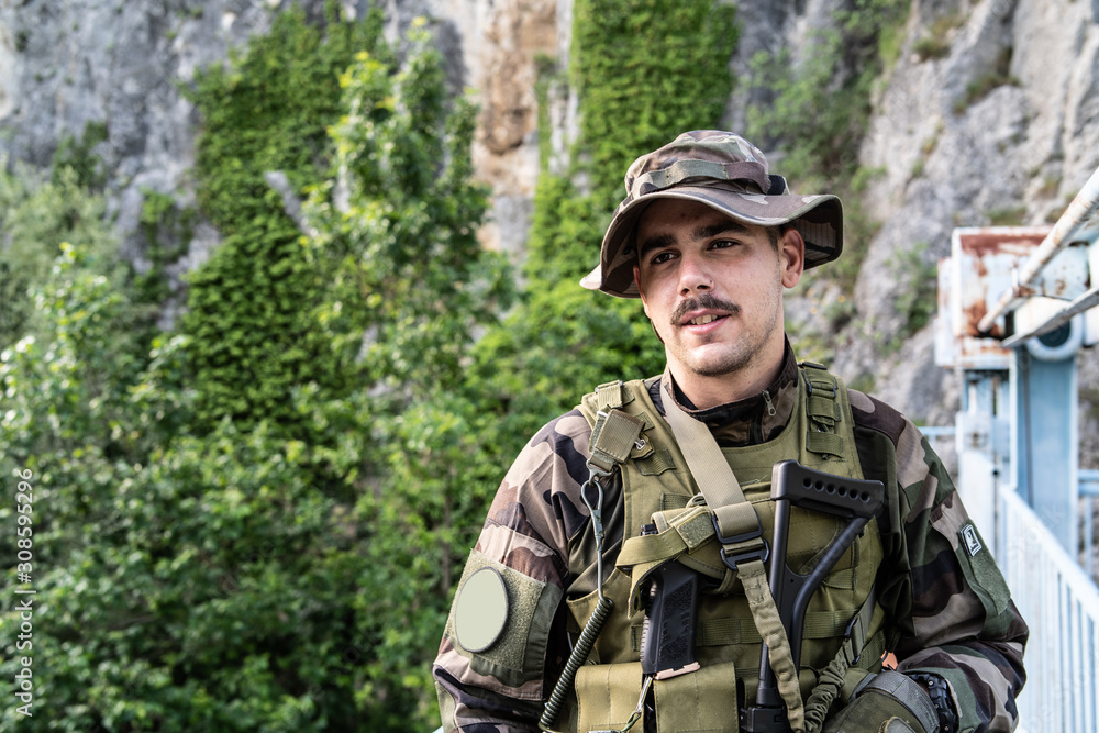 Special force military soldier portrait smiling in battle zone or military practice wearing combat uniform and hat on the bridge in nature guard patrol Special force military soldier portrait smiling in battle zone or military practice wearing combat uniform and hat on the bridge in nature guard patrol
