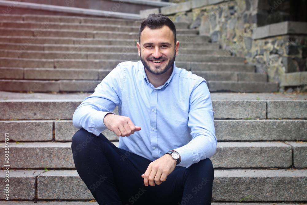 Fototapeta premium Portrait of a bearded man near the big steps of an old European castle. Businessman thinking over a future project. Fashionable guy with stylish clothes.