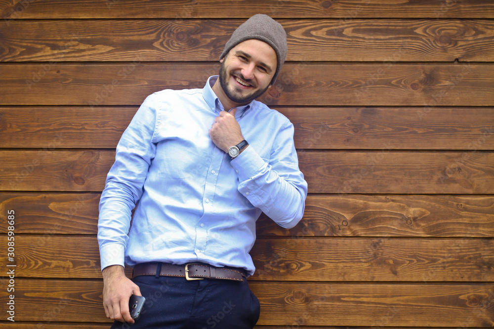 Fototapeta premium Portrait of a handsome man in a shirt on a wooden wall background. Businessman in stylish clothes. Stock Photo for design