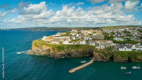 Scenic view of Port Isaac, a coastal town in Cornwall, England. Rocky rugged coast with slate, meadows and coastal paths. Turqoise water with fishing boats.