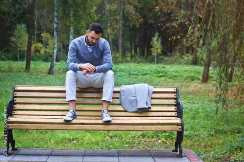 Young sexy guy sitting on a bench in an autumnal, summer park. A man contemplating new ideas while walking. European countryside. Stock Photo © snb2087