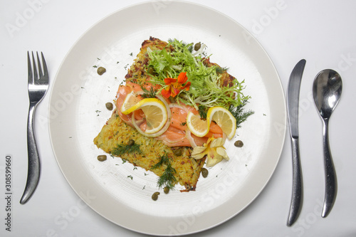 Smoked salmon with potato fritter, decorated with green salad and lemon slices. Exquisite dish. Creative restaurant meal concept. 