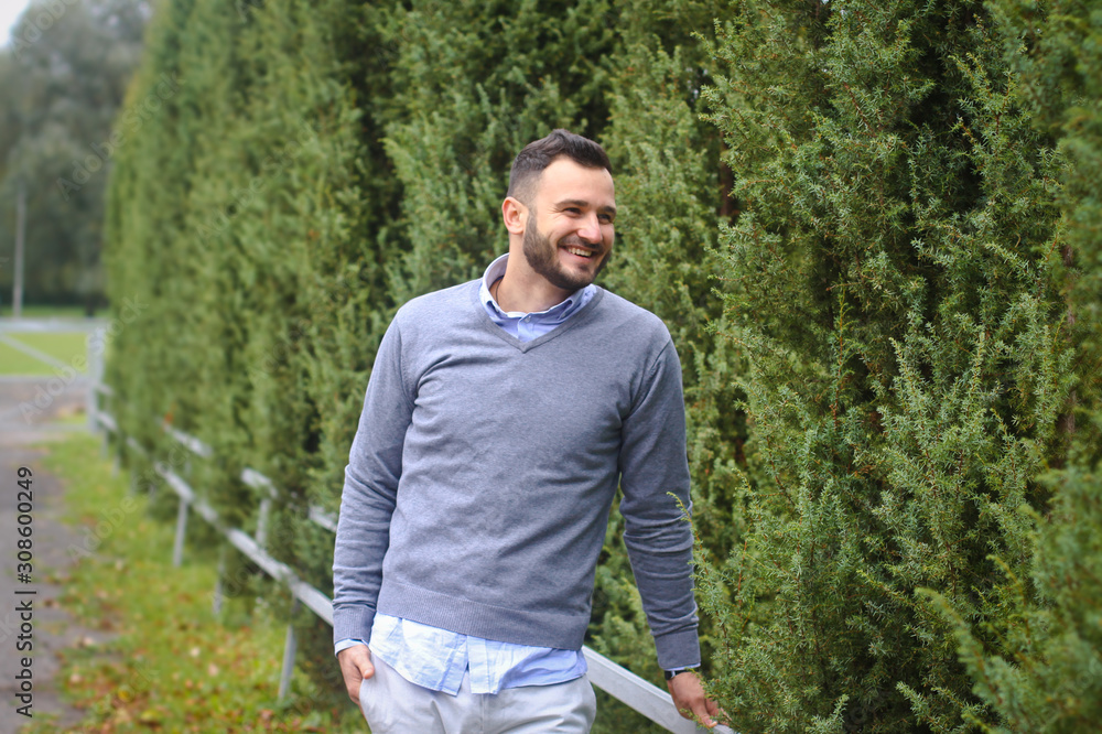 Young guy on the background of European, American city. man in the background of trees and fields and fence. The owner of a beautiful land for business Young guy on the background of European, American city. man in the background of trees and fields and fence. The owner of a beautiful land for business