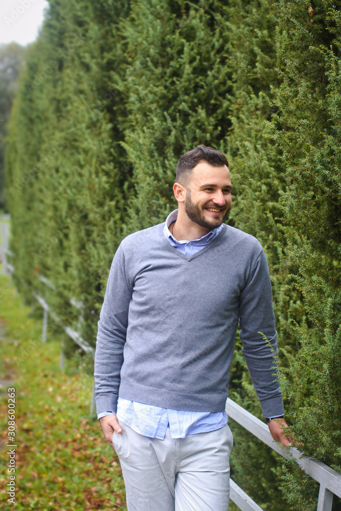 Young guy on the background of European, American city. man in the background of trees and fields and fence. The owner of a beautiful land for business Young guy on the background of European, American city. man in the background of trees and fields and fence. The owner of a beautiful land for business
