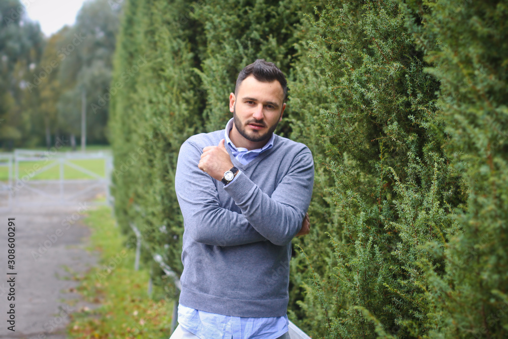 Young guy on the background of European, American city. man in the background of trees and fields and fence. The owner of a beautiful land for business Young guy on the background of European, American city. man in the background of trees and fields and fence. The owner of a beautiful land for business