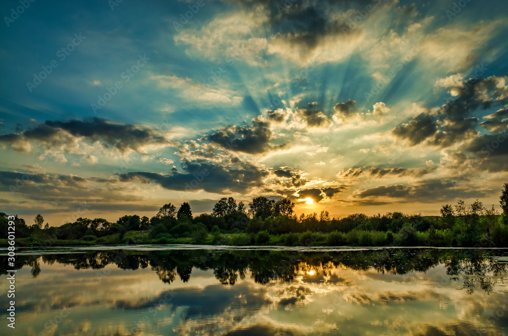 Watching a sunny sunset on the lake, clouds reflected on the water