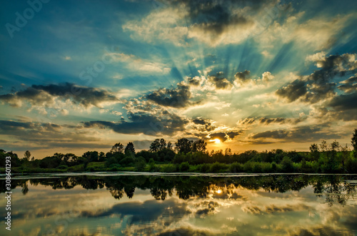 Obraz na płótnie Watching a sunny sunset on the lake, clouds reflected on the water w salonie