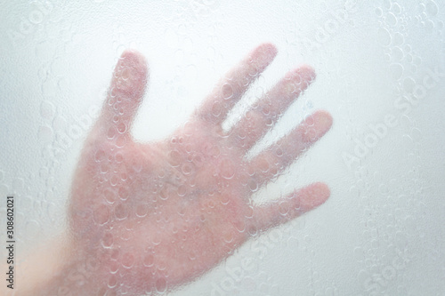 hand through a shower screen with drops on a light background