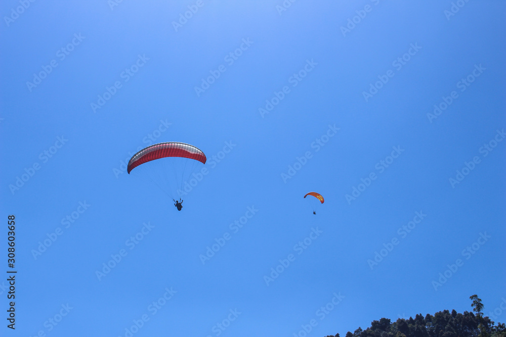 a paraglider flying in blue sky landscape in Indonesia a paraglider flying in blue sky landscape in Indonesia