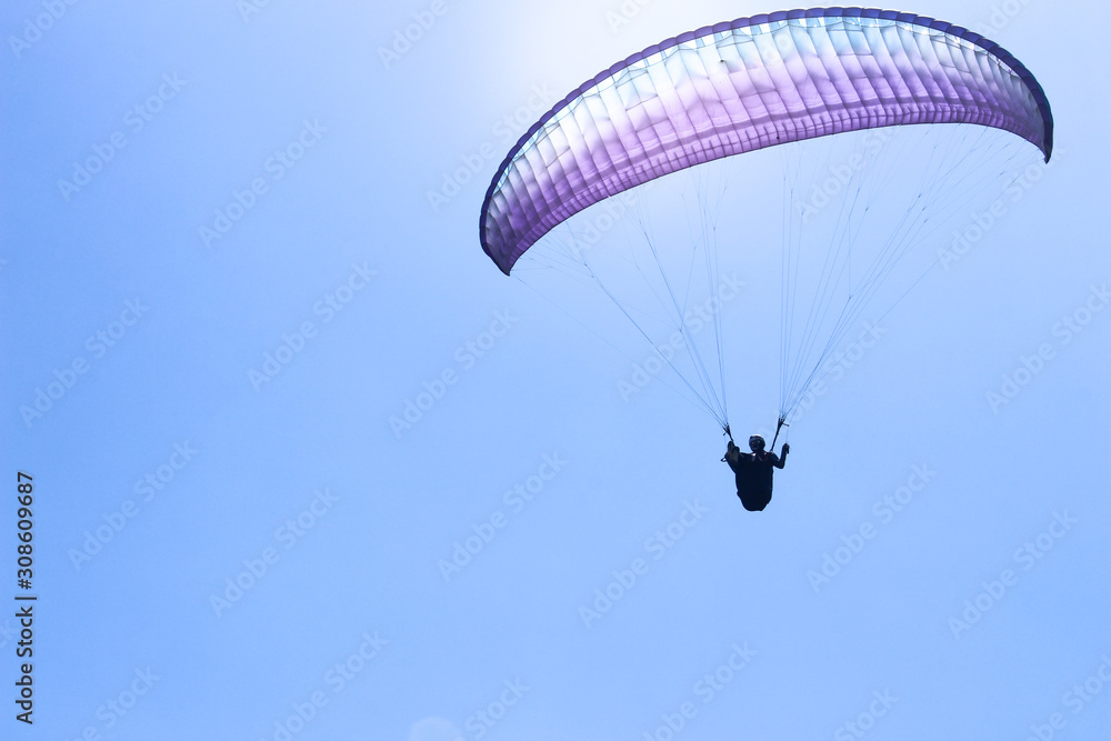 a paraglider flying in blue sky landscape in Indonesia a paraglider flying in blue sky landscape in Indonesia