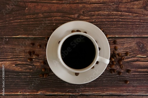 cup of coffee with beans on wooden table
