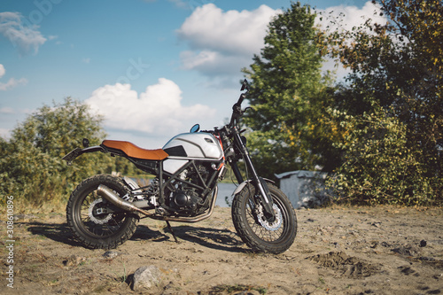 Cafe racer scrambler motorcycle, old fashioned vehicle with modern materials on forest background © Aleksander