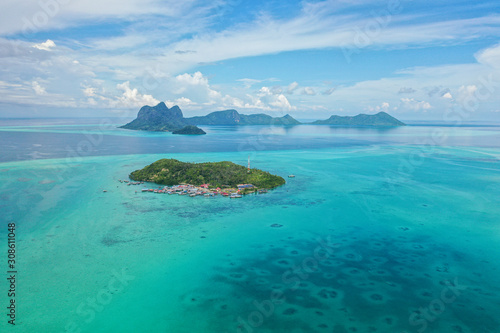 Aerial view of the Selakan island with crystal clear water, blue sky and mountain background in Semporna, Sabah, Malaysia.