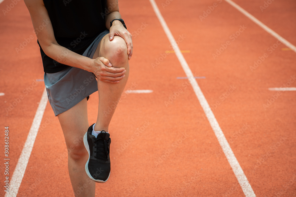 Shot of sport woman holding her knee, suffering from injury, she had
