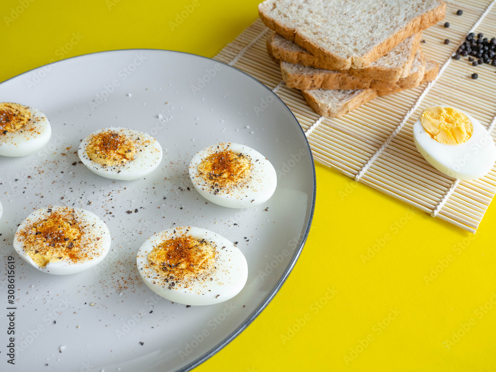 ฺBoiled egg topped with Cayenne pepper Pepper and Salt on a white dish,Egg colors white and yellow,Eat with bread ฺBoiled egg topped with Cayenne pepper Pepper and Salt on a white dish,Egg colors white and yellow,Eat with bread