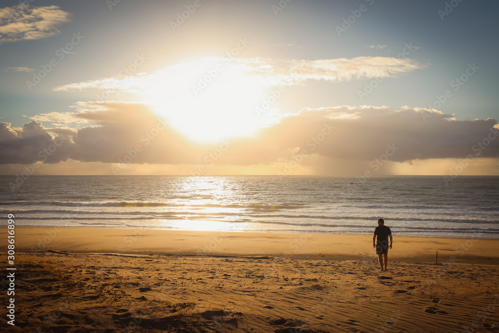 Silhouette of man on beach watching sunrise early in the morning