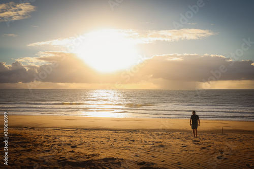 Silhouette of man on beach watching sunrise early in the morning