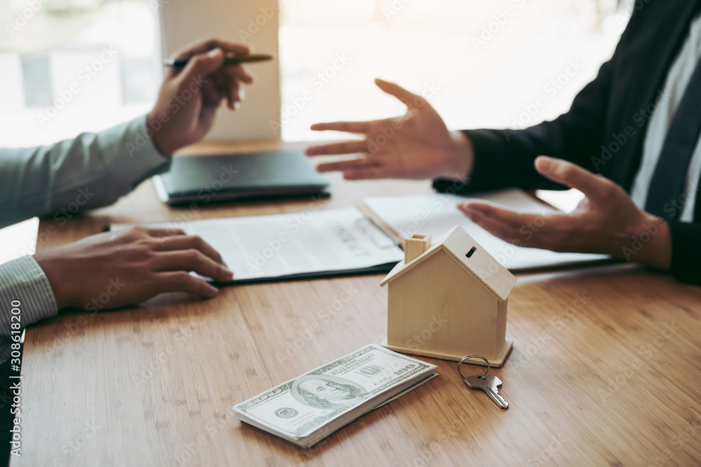 Business people home sales broker is using a pen pointing to the house model and describing the various components of the house. Business people home sales broker is using a pen pointing to the house model and describing the various components of the house.