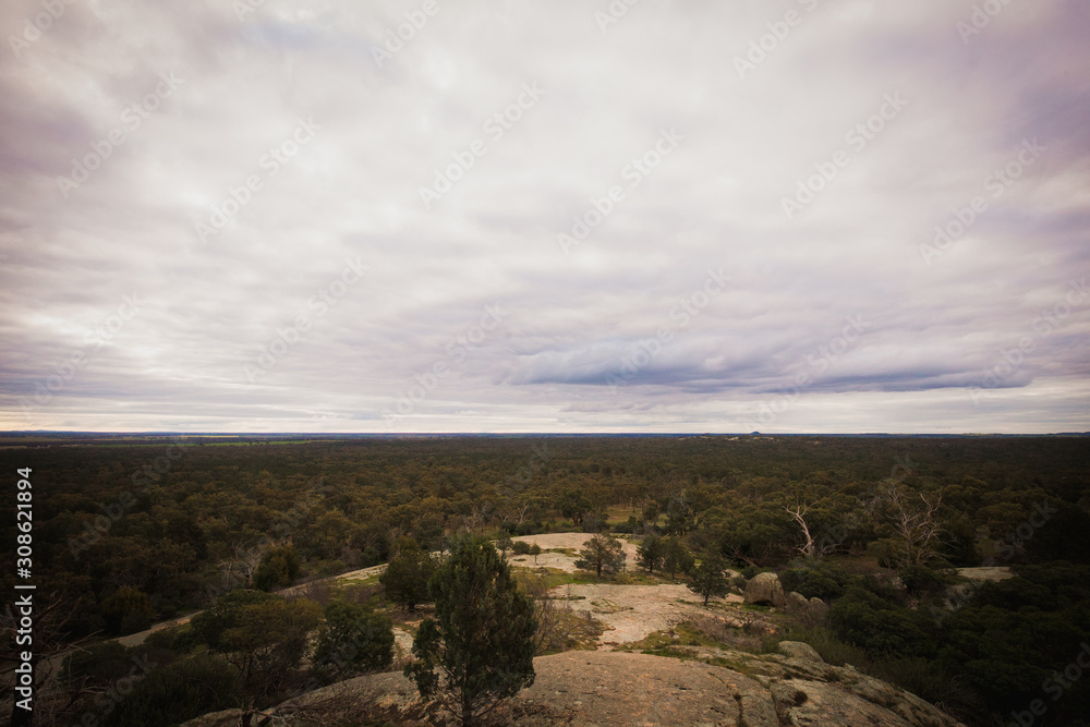 View from the top of a mountain admiring the view of the sweeping landscape below on an overcast day at Terrick Terrick national park in Central Victoria, Australia 