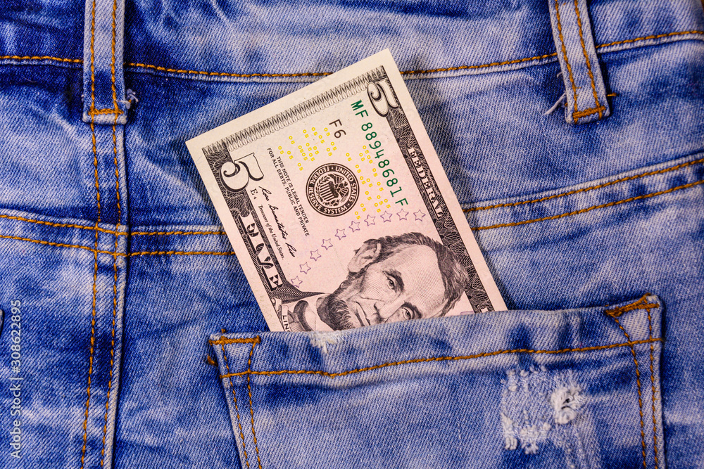 American five dollar banknote in a pocket of blue jeans American five dollar banknote in a pocket of blue jeans