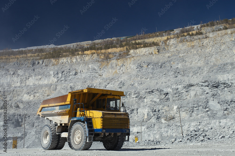Large mining dump truck stands inside a quarry in sunny weather. Large mining dump truck stands inside a quarry in sunny weather.