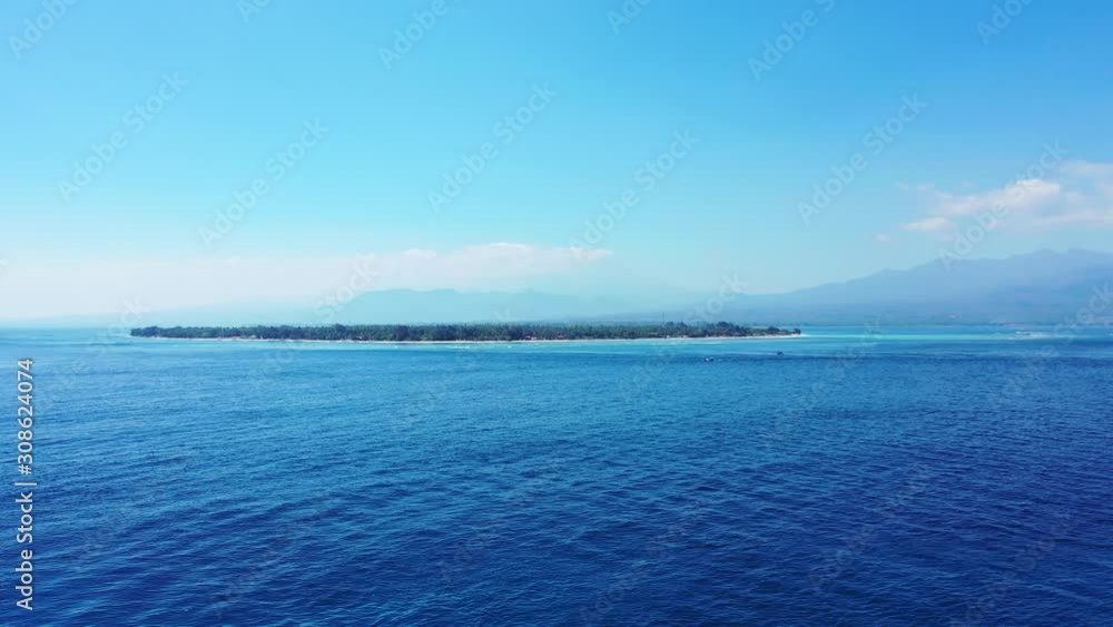 Island In Indonesia - Lush Island Surrounded By Deep Blue Ocean Water With Beautiful Mountain In The Background - Wide Shot