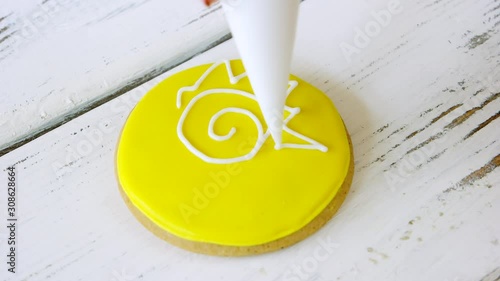 Piping a star on round yellow cookie. Decorated biscuit on wooden surface. The best icing for decoration. photo