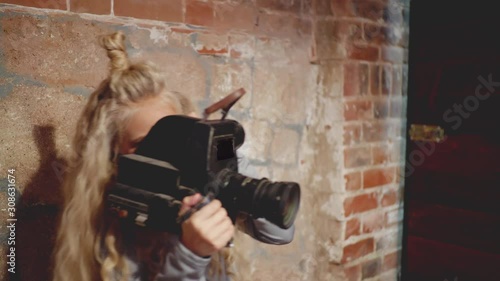 Wallpaper Mural Young female video operator holding black cine camera camcoder. Teenage girl cinematographer standing near brick wall and shooting video with camera Torontodigital.ca