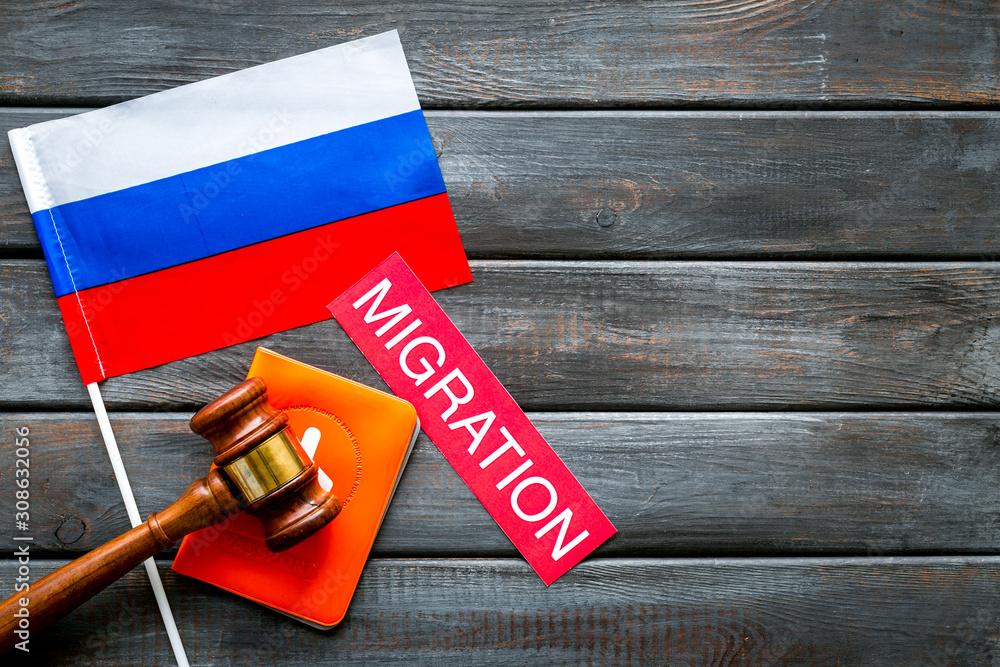 Migration to Russia concept. Russian flag near passport and judge hammer on dark background top-down copy space