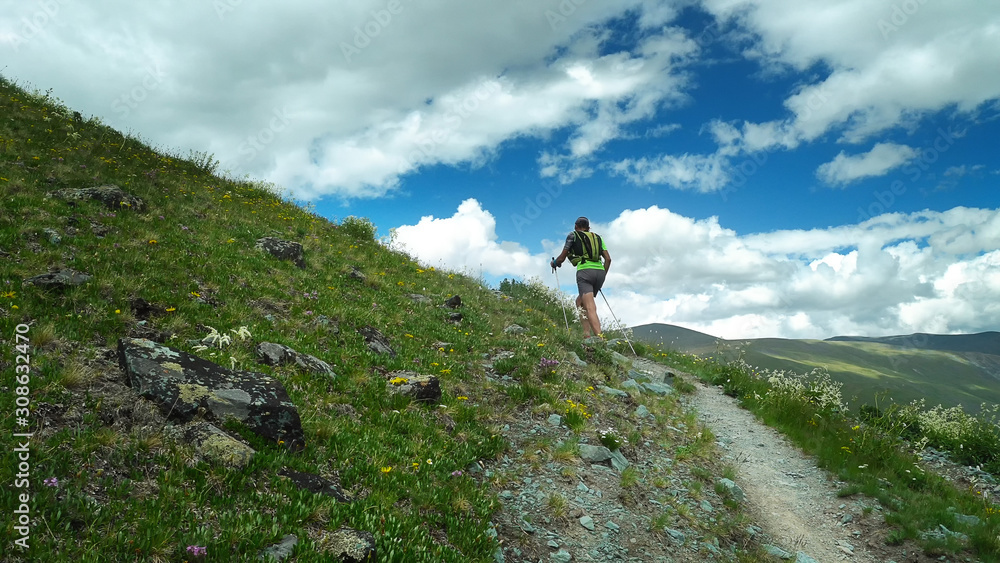Trail runner climbing a stone trail to the mountain top. Ultra trail running, sport activities, mountain trails marathon.