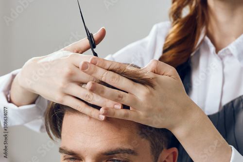 Woman hairdresser doing hairstyle to man