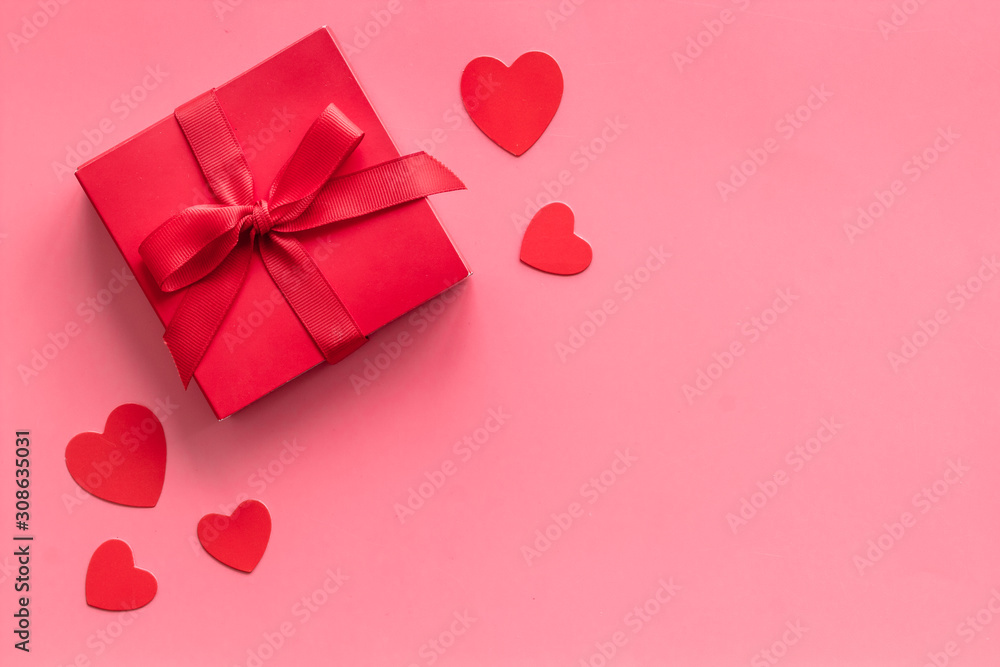 Gift to a sweetheart on Valentine's Day. Red present box near hearts on pink background top-down copy space