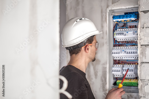Man, an electrical technician working in a switchboard with fuses. Installation and connection of electrical equipment.