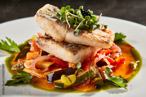 Pollock fish fillet with vegetables on white plate