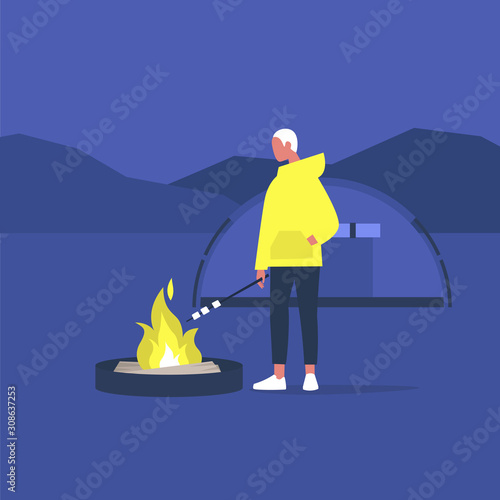 hiking in forest, young male tourist roasting marshmallows on a campfire,