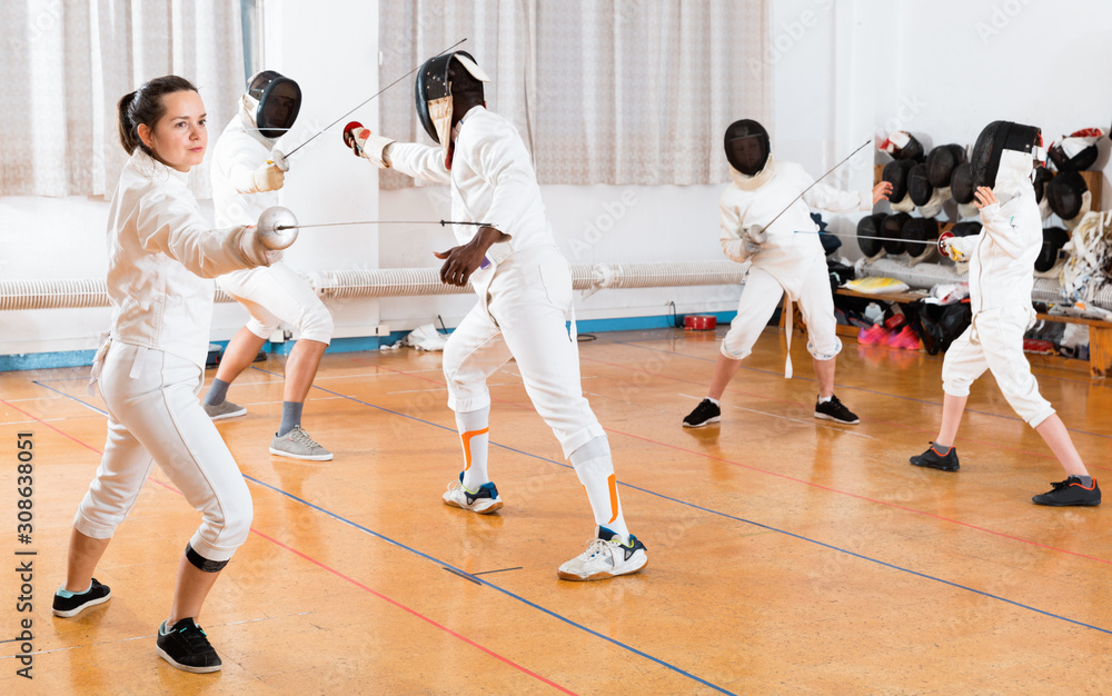 Young woman fencer practicing effective fencing techniques in training room