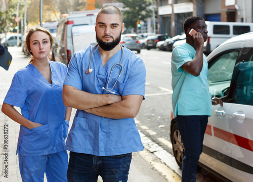 Portrait of concentrated male and female paramedicals near ambulance car0